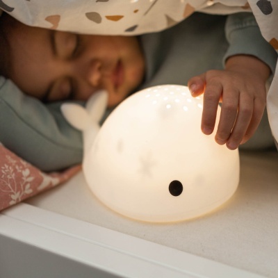 Luz noturna em forma de baleia ao lado de criança a dormir