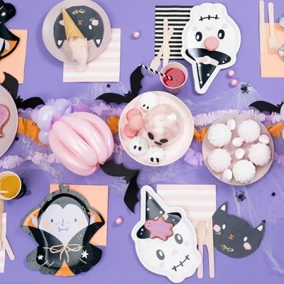 Mesa decorada para festa de Halloween com pratos, copos e guardanapos temáticos em preto, branco, rosa e laranja.