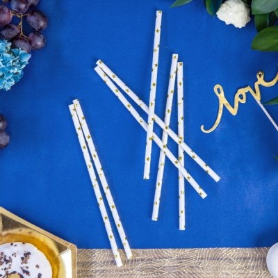 Canudos de papel branco com estrelas douradas em tecido azul com flores, frutas e objetos decorativos