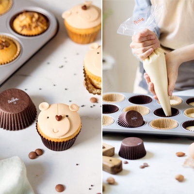 Cupcakes decorados e mão a preparar cupcakes com saco de pasteleiro