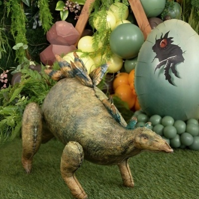 Estátua de dinossauro Stegosaurus e decoração com balões e relva
