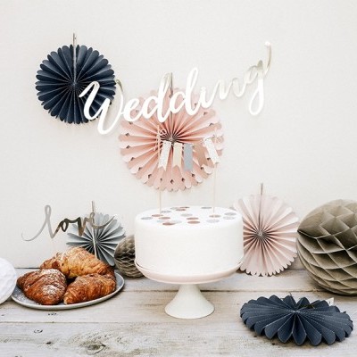 Mesa decorada com bolo branco e croissants, papel decorativo em tons neutros e palavras Wedding e love na parede