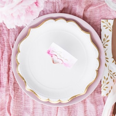 Conjunto de prato, guardanapo e talheres dourados sobre toalha rosa