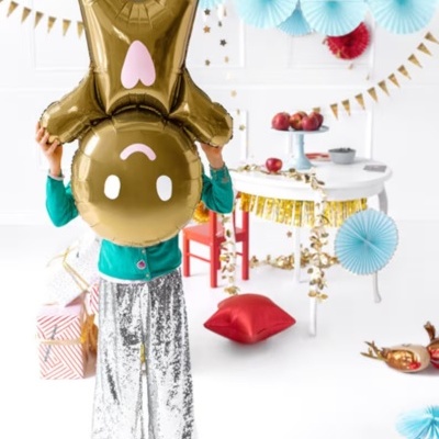 Criança com balão metálico dourado em forma de coelho num ambiente festivo