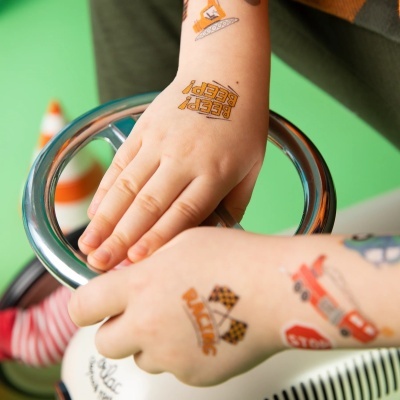 Mãos de criança com tatuagens temporárias com tema de veículos e corrida