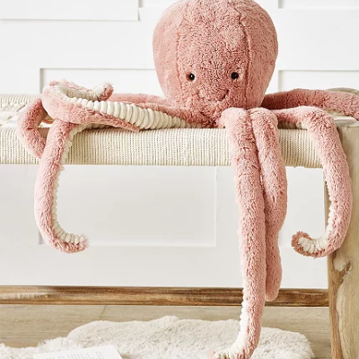 Polvo de peluche cor-de-rosa sobre banco claro com tapete e livro no chão