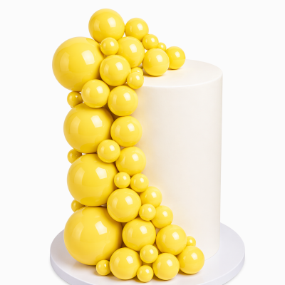 Bolo branco cilíndrico decorado com esferas amarelas brilhantes de vários tamanhos