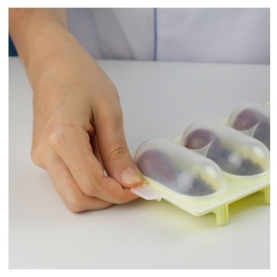 Forma de gelo de silicone com frutas dentro, mão a puxar a forma