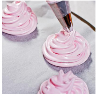 Aplicação de creme rosado com manga de pasteleiro sobre papel vegetal