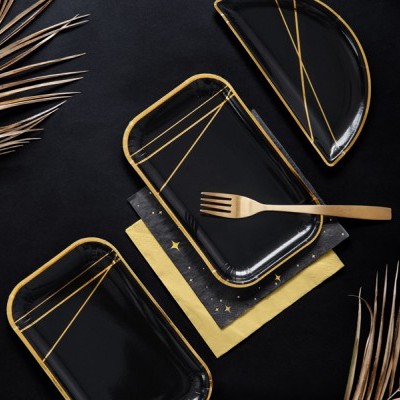 Três pratos pretos com bordas douradas e garfo dourado sobre guardanapos e folhas secas