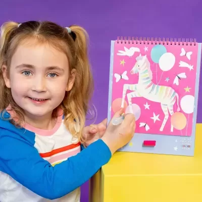 Caderno artístico rosa com zebra colorida e menina usando caneta mágica