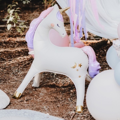 Unicórnio insuflável branco com crina lilás e detalhes dourados em área externa
