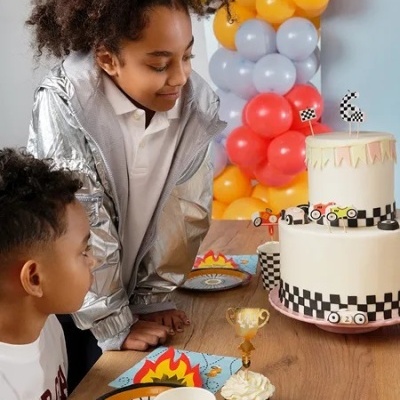 Dois miúdos em festa com bolo e decoração temática de corrida