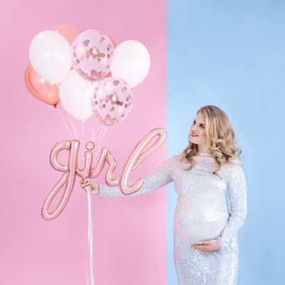 Mulher grávida com vestido prateado segurando balões cor-de-rosa, branco e 