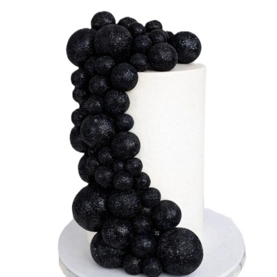 Bolo branco com esferas negras brilhantes como decoração