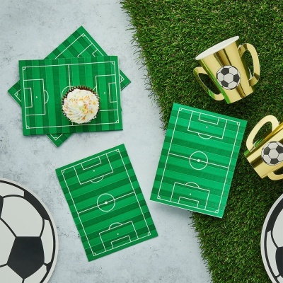 Artigos de festa com tema de futebol em verde e dourado sobre superfície de grama sintética