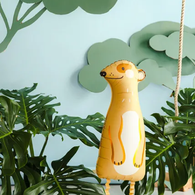 Balão insuflável amarelo em forma de suricato em cenário com folhas e árvores decorativas