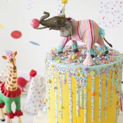 Bolo amarelo com elefante decorativo colorido em cima