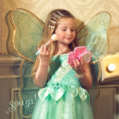 Menina com vestido e asas de fada verdes segurando pincel e espelho cor-de-rosa