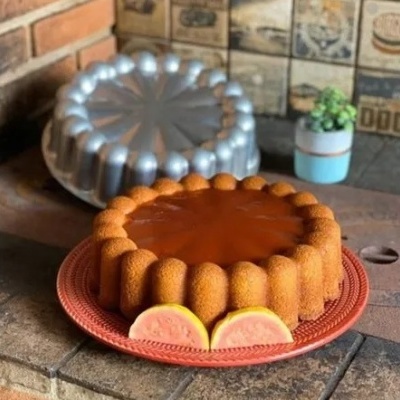 Bolo redondo com cobertura e fatias de fruta em prato vermelho