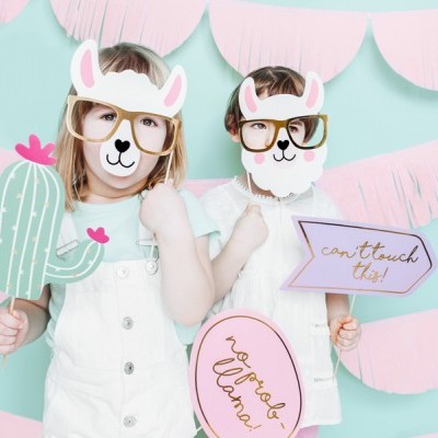 Crianças com máscaras de unicórnio e adereços de festa coloridos em fundo azul claro e decoração rosa