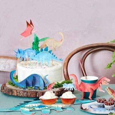 Bolo decorado com figuras coloridas de dinossauros em papel numa festa infantil