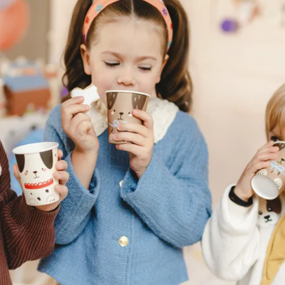 Crianças segurando copos de papel com desenhos de animais em ambiente interno