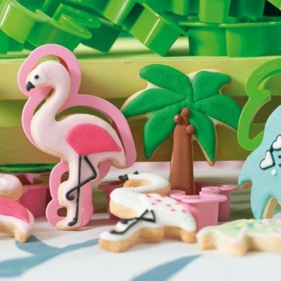 Biscoitos decorados em forma de flamingo, árvore e balde em ambiente colorido.