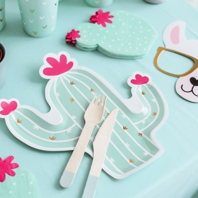 Placa cacto azul claro com talheres de madeira e máscara com óculos sobre mesa azul