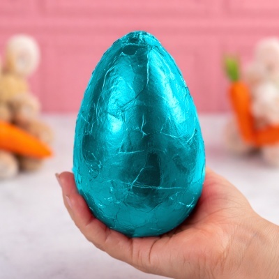 Ovo de Páscoa azul embalado em papel brilhante segurado pela mão