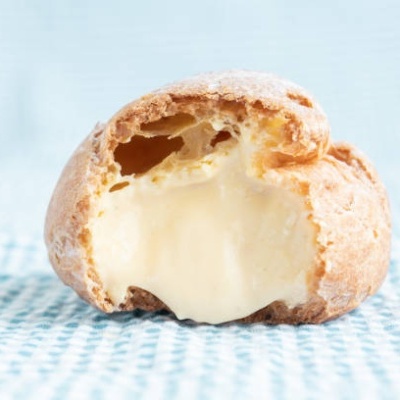 Profiterol partido mostrando recheio cremoso amarelo claro