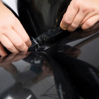 Mãos a ajustar uma correia preta num material brilhante e preto