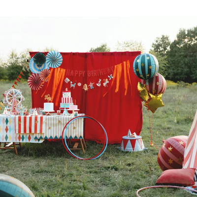 Mesa e decoração festiva com toalha estampada, bolo, balões e cortina vermelha com HAPPY BIRTHDAY