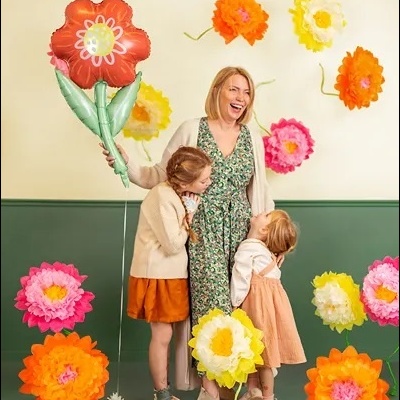 Mulher e duas crianças com flores decorativas de papel coloridas em estúdio