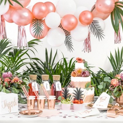 Mesa decorada para festa com bolo, copos com bebidas, arranjos florais, balões rosa e branco e acessórios