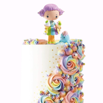 Bolo branco com flores coloridas em glacê e figuras infantis no topo