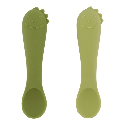 Duas colheres de silicone verde com design de dinossauro sorridente em fundo branco