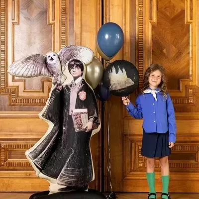 Figura insuflável de Harry Potter e criança com balões em fundo de madeira trabalhada.