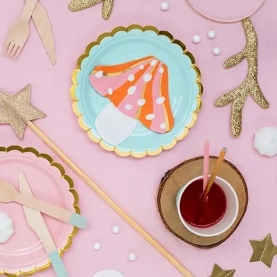 Artigos de festa coloridos com temas de cogumelo e decoração dourada em fundo cor-de-rosa