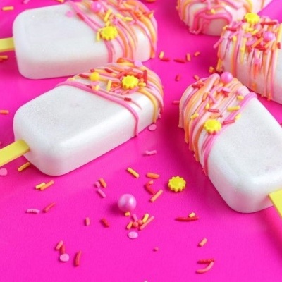 Gelados brancos com decoração rosa e amarela sobre fundo rosa