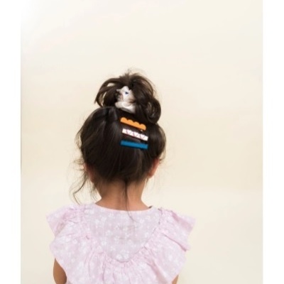 Criança com cabelo preso e roupa rosa vista de costas