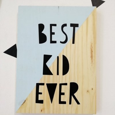 Placa decorativa retangular com texto 'BEST KID EVER' em madeira e azul claro