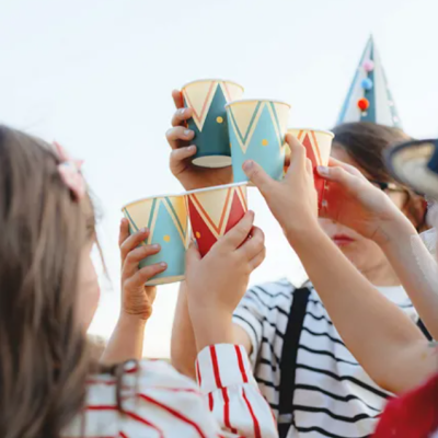 Crianças a brindar com copos de papel coloridos em festa