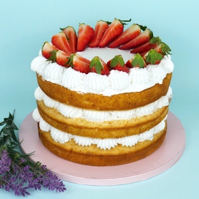 Bolo de três camadas com creme branco e morangos frescos.
