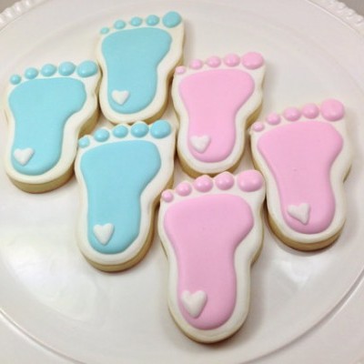 Bolachas decoradas em forma de pés azul e rosa num prato branco