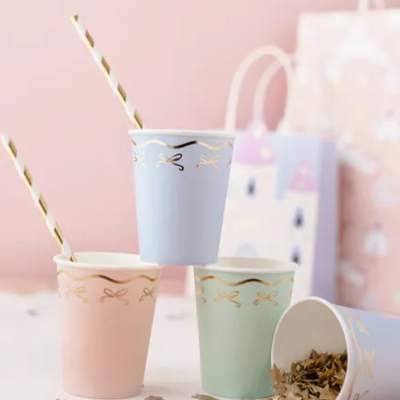 Copos descartáveis em cores pastel decorados com laços dourados e canudo riscado