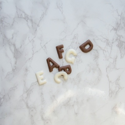 Letras de chocolate em branco e castanho sobre fundo marmoreado