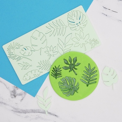 Moldes para modelagem de folhas tropicais em silicone sobre fundo azul e branco com detalhe em mármore