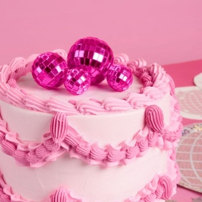 Bolo rosa com decoração de creme e bolas brilhantes cor de rosa no topo