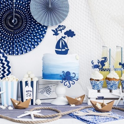 Mesa decorada com tema náutico azul e branco com bolo, copos decorados e barcos de papel